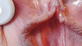 Bidikan close-up dari klitoris halus dan basah sedang masturbasi